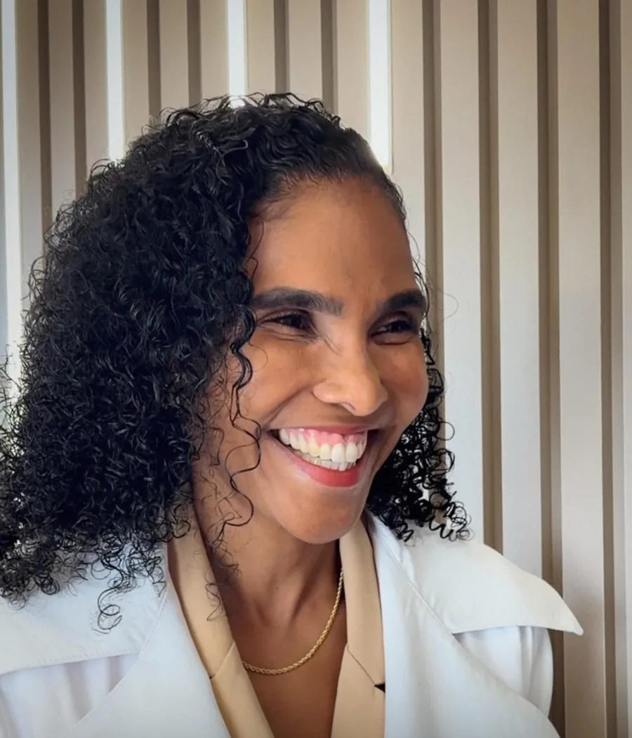 Dra. Rosana Frempong sorrindo, de jaleco branco, no consultório