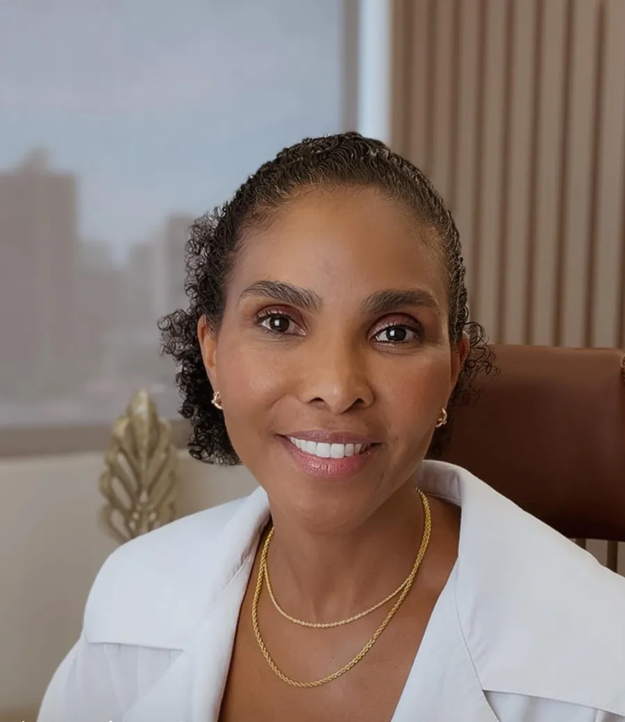 Dra. Rosana Frempong sentada à mesa do consultório, sorrindo