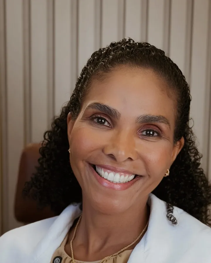 Dra. Rosana Frempong sorrindo, de jaleco branco, no consultório