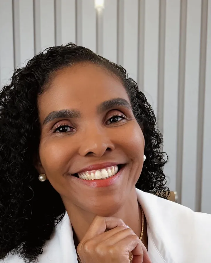 Dra. Rosana Frempong sorrindo, com a mão apoiada no queixo, de jaleco branco