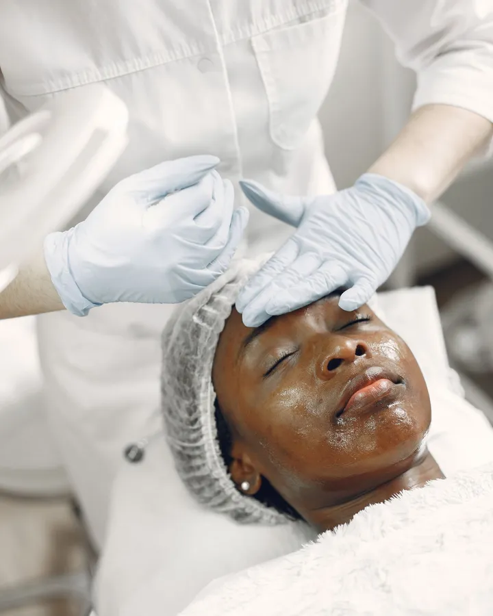 Paciente negra de olhos fechados durante um cuidado facial em clínica