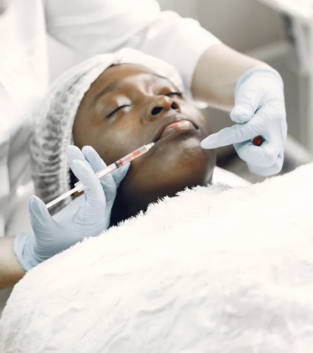 Paciente negra recebendo aplicação facial minimamente invasiva em ambiente clínico