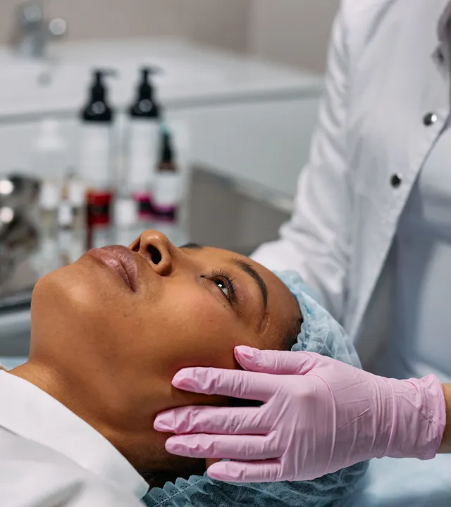 Profissional avaliando o contorno do rosto de uma paciente negra em ambiente clínico
