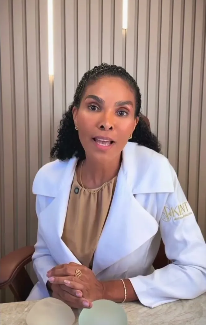 Dra. Rosana Frempong à mesa do consultório, com implantes mamários de silicone sobre a mesa